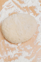 Prepared kneaded dough on a wooden table at home