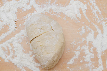 Prepared kneaded dough on a wooden table at home