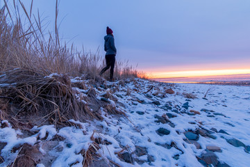 Winter sunrise on Drakes Island Beach, Maine with person silhouette.
