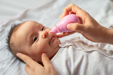 mother using baby nasal aspirator mucus nose suction