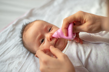 mother using baby nasal aspirator mucus nose suction