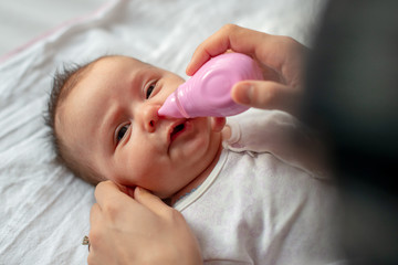 mother using baby nasal aspirator mucus nose suction - obrazy, fototapety, plakaty