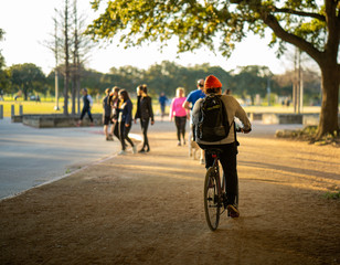 A man rides his bicycle through a park at sunset