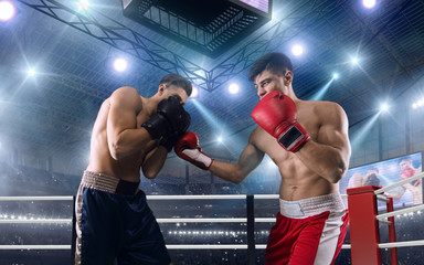 Fototapeta na wymiar Two boxers are fighting on professional boxing ring.