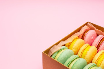 Macaron or Macaroon is a popular French dessert in a gift box on a pink background. There is copy space