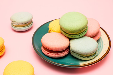 Fototapeta na wymiar Fresh bright colored Macarons, or macaroons on a plate, on a pink background