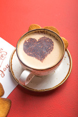 Cup of fresh morning coffee  with Valentine's day card and heart cookies, on red background copy space.