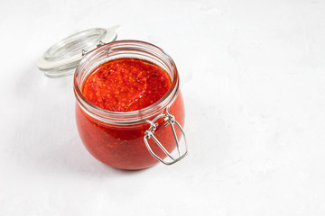 Hot chili pepper sauce paste harissa. Adjika. Traditional Tunisia, Georgian and Arabic cuisine. Homemade rose harissa in a glass jar.