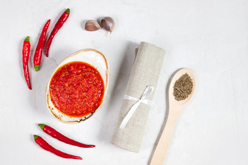 Hot chili pepper sauce paste harissa. Adjika on a white background. Traditional Tunisia, Georgian and Arabic cuisine. Homemade rose harissa in a bowl.