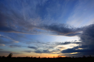 Burzowe chmury na błękitnym niebie w czasie zachodu słońca.