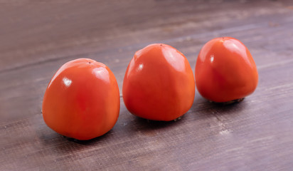 Persimmon - orange  color fruits on brown table