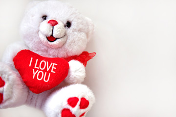 I love you - text on the red heart of a white toy bear