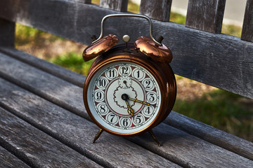Naklejka premium Vintage alarm clock on a wooden bench