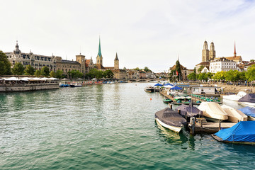Limmat River Quay with boats and three main churches of Zurich - Grossmunster, Fraumunster and St Peter Church. Switzerland