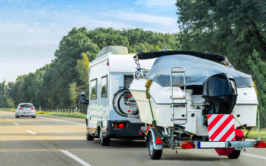 Caravan and trailer for motor boats on the road in Switzerland. - 320161187