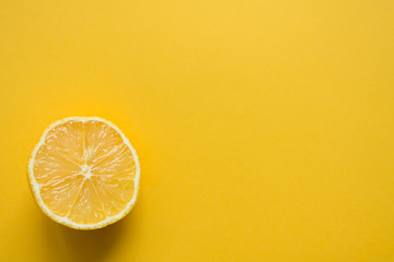 Half of a juicy ripe lemon in close-up on a bright yellow background with space for copying