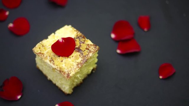 Ciasto drożdżowe na czarnym tle, posypany płatkami czerwonych r&oacute;ż, panorama