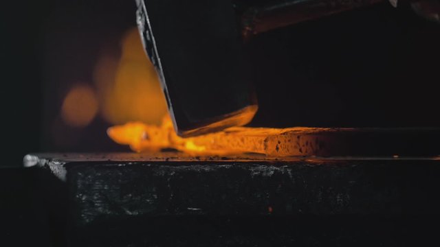 Forge workshop. Smithy manual production. Hands of smith with hammer hit on glowing hot metal, on the anvil, the forging process. Blacksmith makes iron products for manufacture of fireplace, stove.