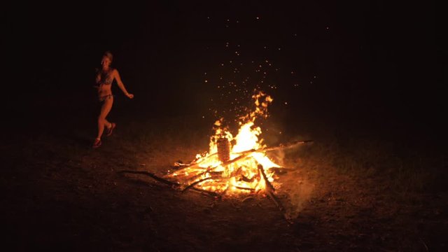 Silhouette of mystic woman in black background of fire fly flame, spark, of contour outline. Adult sexy of young girl witchcraft ceremony ritual dance in underclothes. Outdoor slow motion. Caucasian.