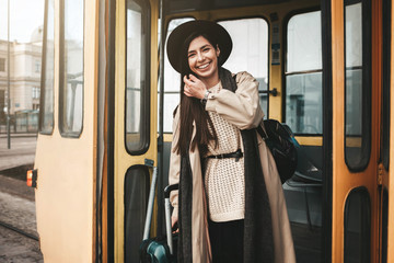 Beautiful stylish girl traveler with suitcase gets off the tram