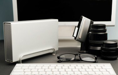 Obraz na płótnie Canvas concept work table photographer, composition, silver-colored desktop hard drive with spectacles, 80mm photographic lens, compacflash cards downloader, 50mm photographic lens, partial computer view, 
