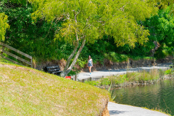 Fototapeta na wymiar Teenage girl walking towards along a path around lake at McLaren Falls Park, Tauranga New Zealand