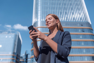 Fototapeta premium happy young woman with smartphone on modern building background