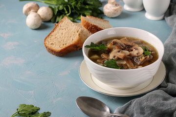Mushroom soup of champignons and lentils in a white plate on a light blue background, Copy space