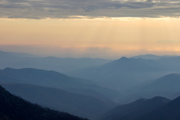 Fototapeta na wymiar Soft, colorful view of distant mountain layers in Bulgaria from Old mountain in Serbia, lighten by morning sun rays under dramatic, vibrant sunrise sky