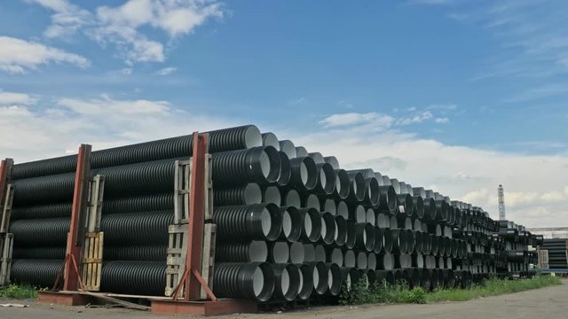 Warehouse of finished plastic pipes industrial outdoors storage site. Manufacture of plastic water pipes factory. Process of making plastic tubes on the machine tool with the use of water and air