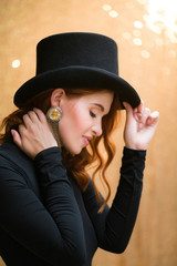 A girl with red hair in an Art Deco style dressed in a black dress and a black top hat with a shiny...