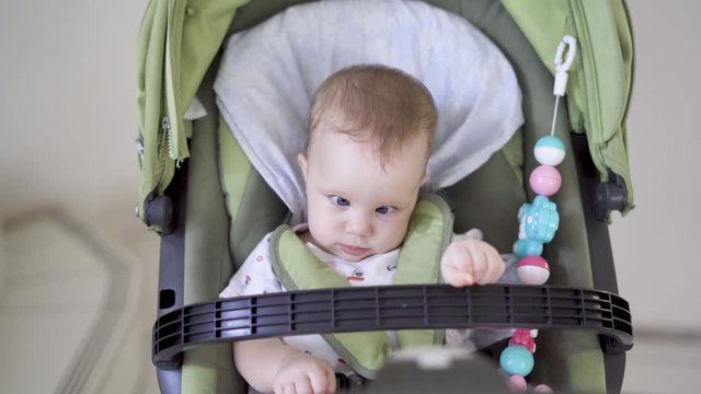 Cute baby girl looking at the camera while while sitting in the stroller. Shot in 4k resolution
