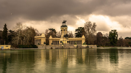 Fototapeta na wymiar View of the monument of Alfonso XII from the other side of the pond, in the Retiro Park in Madrid. Travel concept.