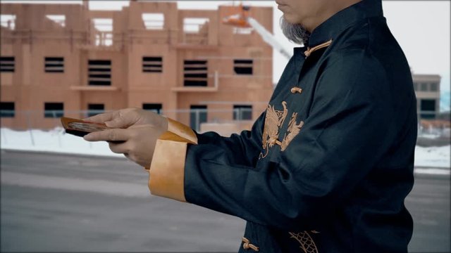 Feng Shui Master checks the Lo-Pan compass to be sure that nature's energy force is in harmony with a housing construciton project - winter