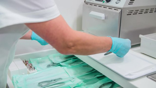 Pedicure technician takes stainless steel nail clipper out of sterile plastic wrap