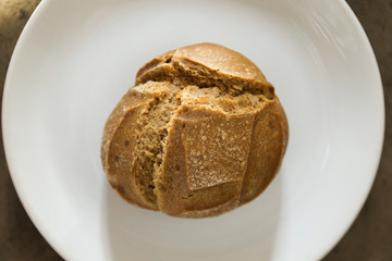 Soft fresh baked white bread with a crispy crust on a white plate on textured table