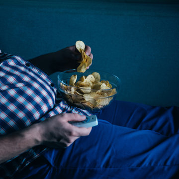 Overeating, Sedentary Lifestyle, Bad Habits, Food Addiction, Eating Disorders. Fat Overweight Man Lay On The Coach With Tv Remote And Junk Food. Depression, Laziness