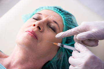 Naklejka premium Old woman visiting male doctor for plastic surgery