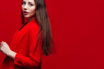 Bright and beautiful girl in a red pantsuit on a red background