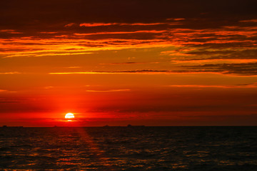 Merchant ships on the horizon against the background of a fiery red sunset
