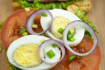 Three Sandwich with ham and tomatoes on wooden board.