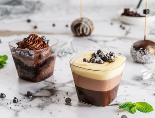 Tasty cream mousse dessert with chocolate in a glass on light background close up. Delicious dessert and candy bar, close up
