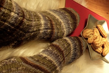 Fototapeta na wymiar Low Section Of Person Wearing Woolen Sock By Cookies In Star Shape Plate