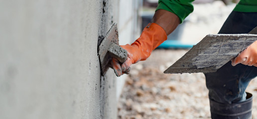 closeup hand worker plastering cement on wall for building house - obrazy, fototapety, plakaty