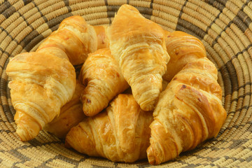 Close up of bunch of breakfast croissant pastries in woven basket