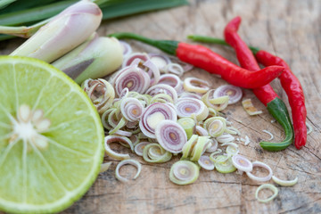 Red chilli lemongrass and green lemon on wooden cutting board.