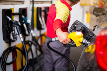 Yellow oil nozzle in gas station. Hands refilling the car with fuel at the gas  station, black car...