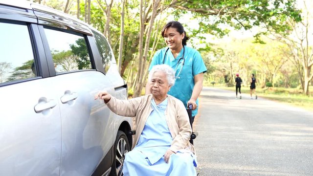 Help and support asian senior or elderly old lady woman patient sitting on wheelchair prepare get to her car : healthy strong medical concept.