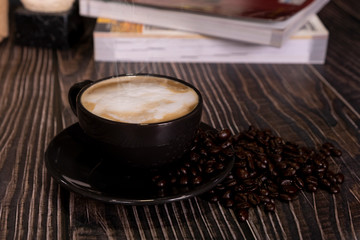 Hot latte coffee with roasted coffee beans on a wooden table
