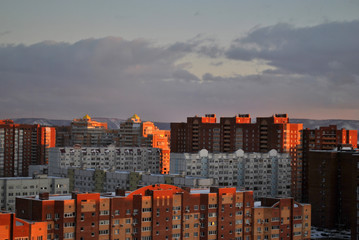  Evening view of high-rise apartment buildings on the banks of the Volga River in the rays of the setting sun.